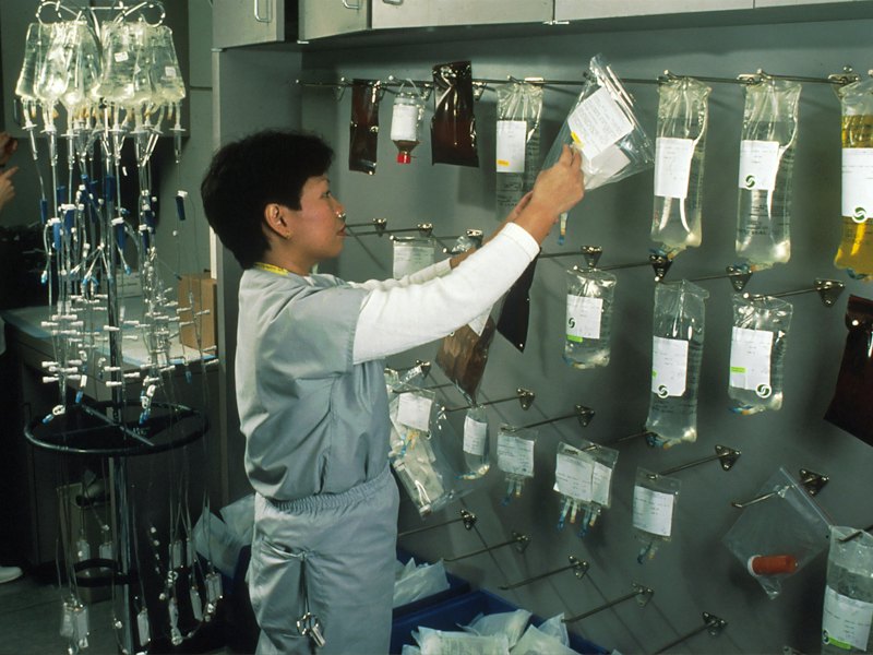 A pharmacist arranging IV bags on a clinic wall rack