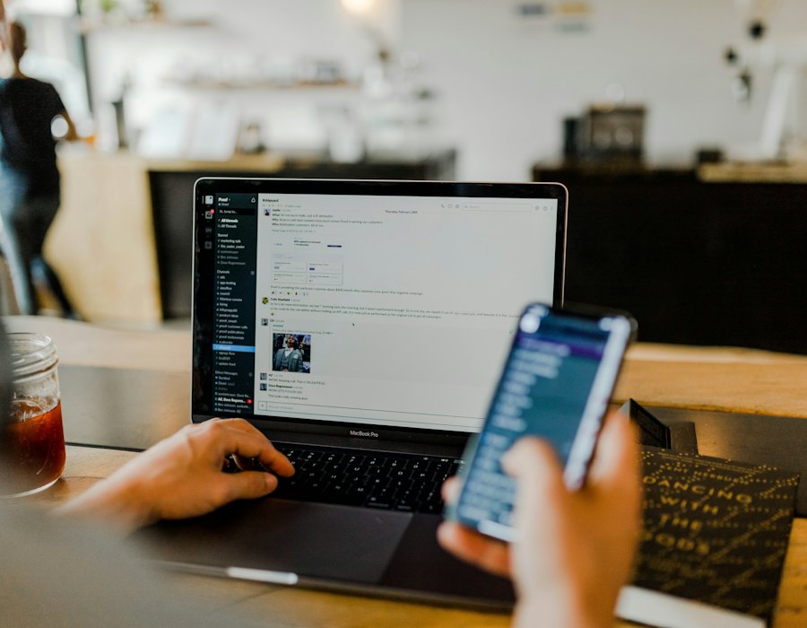 A staff member messaging support from a laptop and phone